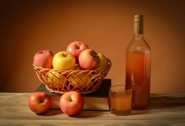 Durgun hayat, sepetteki elmalar ve tahta masada elma suyu.