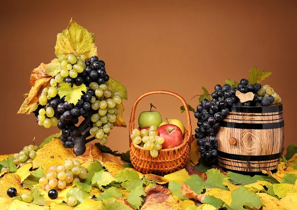 Grapes in a wicker basket and apples — Stock Photo, Image