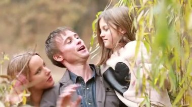 Aile gülümseyen ve parkta sallayarak