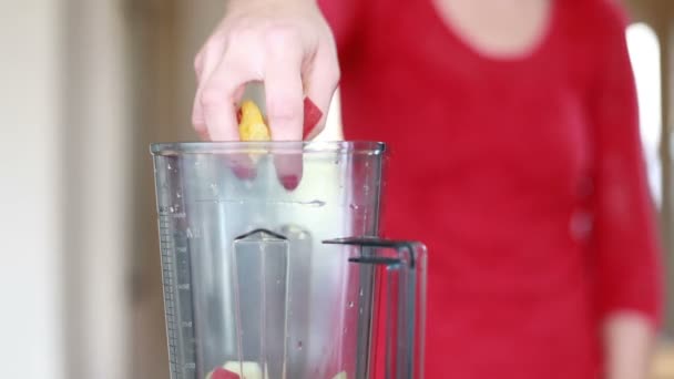 Женщина кладет фрукты в блендер — стоковое видео