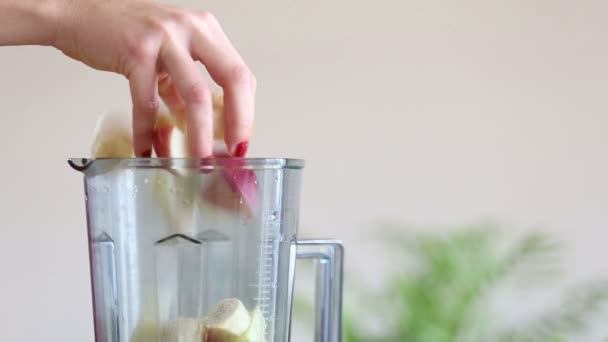 Vrouw zetten van fruit in de blender — Stockvideo