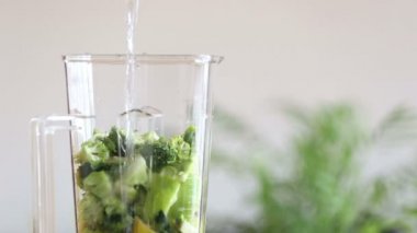 Pouring water in blender with fruits