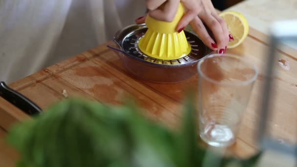 Женщина сжимает лимон на соковыжималке — стоковое видео