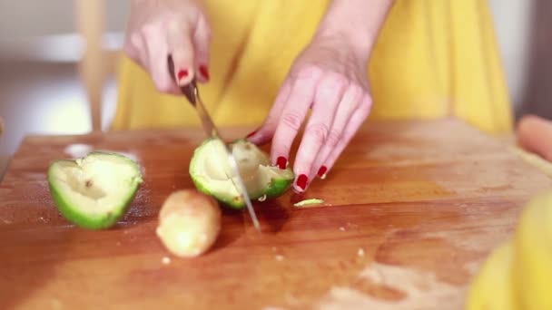 Frau schneidet Avocado mit der Hand — Stockvideo