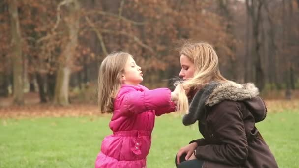 Girl putting hands through mother 's hair — стоковое видео