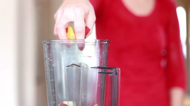 Woman putting fruits into blender — Stock Video