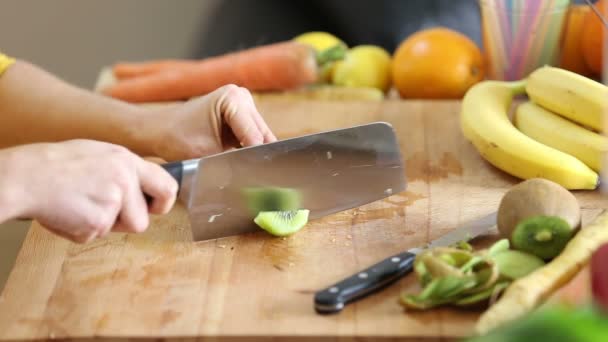 Frau schneidet Kiwi in Stücke — Stockvideo