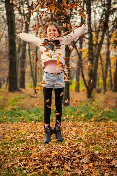 Kind speelt met bladeren in park — Stockfoto