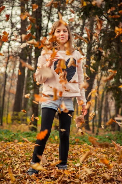 Kind speelt met bladeren in park — Stockfoto