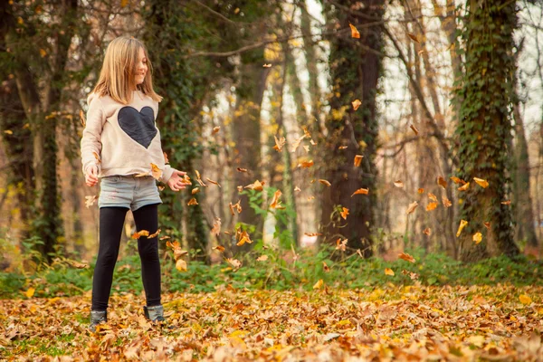 Child plays with leaves in park — Stock Photo, Image