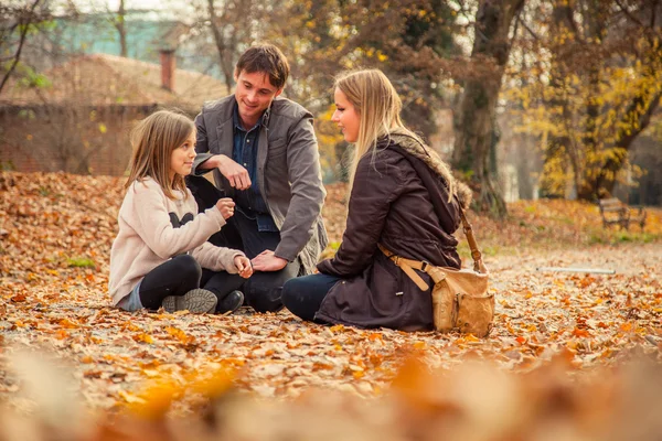 Familie kniet auf Parkgelände — Stockfoto