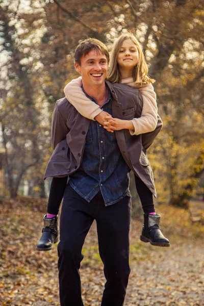 Daughter rides father on piggyback — Stock Photo, Image