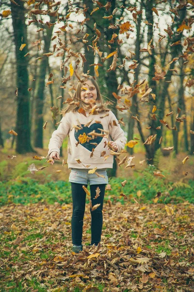 Child plays with leaves in park — Stock Photo, Image