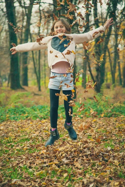 Kind speelt met bladeren in park — Stockfoto