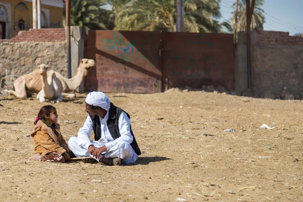 Camel salesman and girl sitting on the ground — Stock Photo, Image