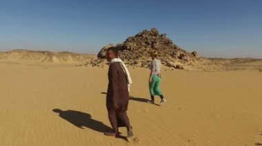 turist ile çölde yürüyen Nubia'lı adam