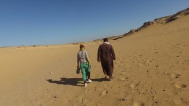 turist ile çölde yürüyen Nubia'lı adam