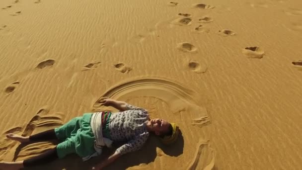 Vrouw maken van zand engel in de woestijn — Stockvideo