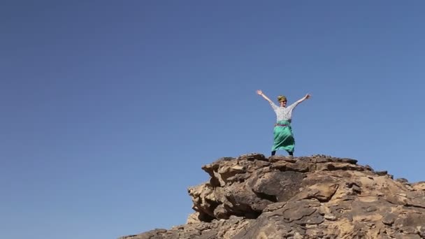 Turista extendiendo brazos en gran roca en el desierto — Vídeo de stock