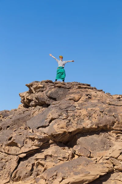 Tourist spreading arms on big rock in desert — Stock Photo, Image