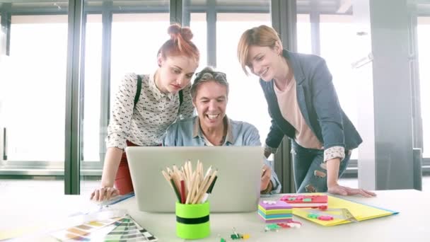 Directeur créatif regardant ordinateur portable avec l'équipe — Video