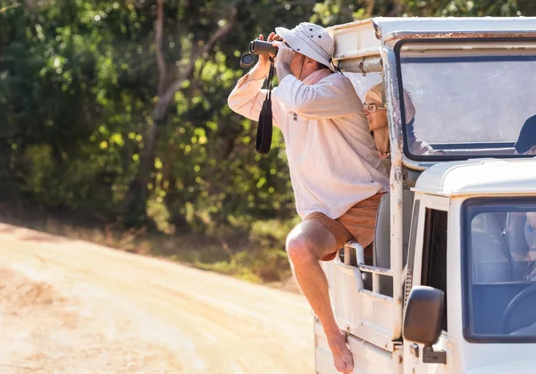 Turista během tour safari v parku Jala při pohledu dalekohledem — Stock fotografie