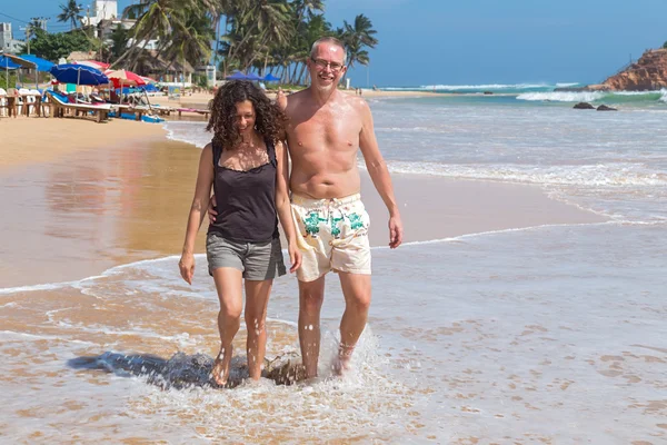 Tourist  couple walk on sandy beach — Stock Photo, Image