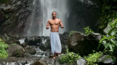 Şelale altında Yoga yapan erkek