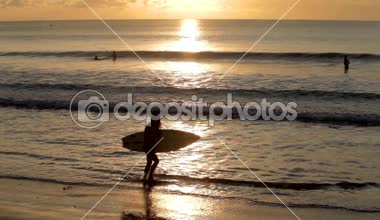 Surfboard ile kumsalda yürüyen kadın