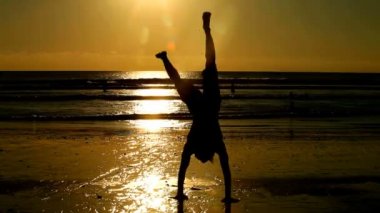 Genç adam sahilde egzersizleri yapıyor