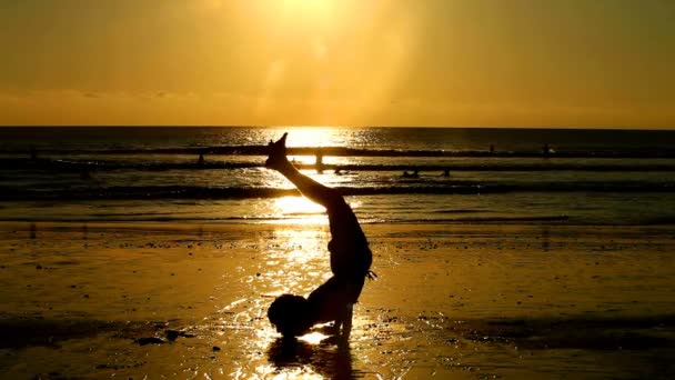 Silhouet van jonge man doen oefeningen op strand bij zonsondergang, Bali — Stockvideo