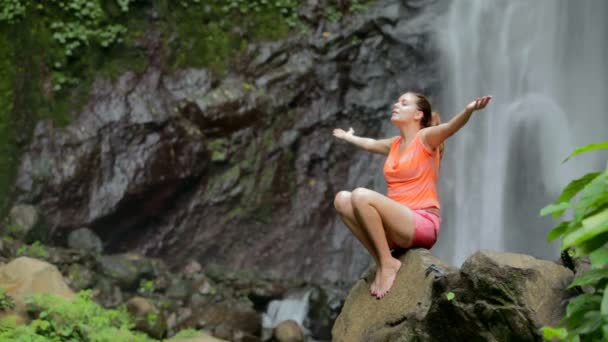 Frau sitzt in Meditation unter Wasserfall — Stockvideo