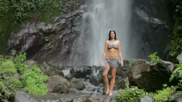 Жінка стоїть під водоспадом — стокове відео