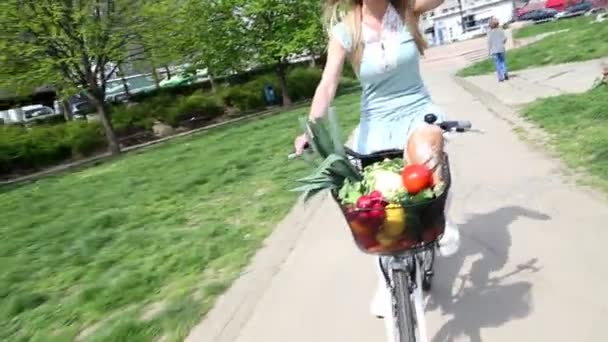 Chica montando bicicleta y sosteniendo un sombrero — Vídeos de Stock