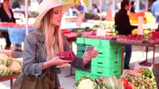 Девушка на рынке платит за овощи — стоковое видео
