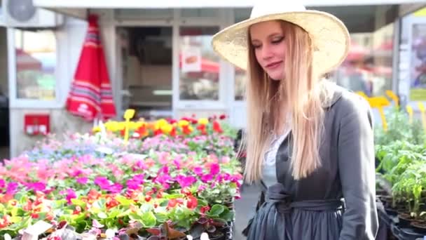 Девушка смотрит на цветы на рынке — стоковое видео