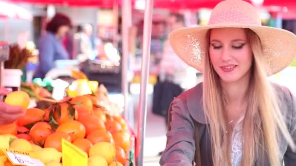 Девушка на рынке собирает фрукты — стоковое видео