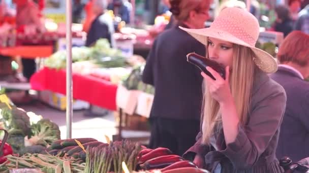 Chica en el mercado, oliendo berenjenas — Vídeos de Stock