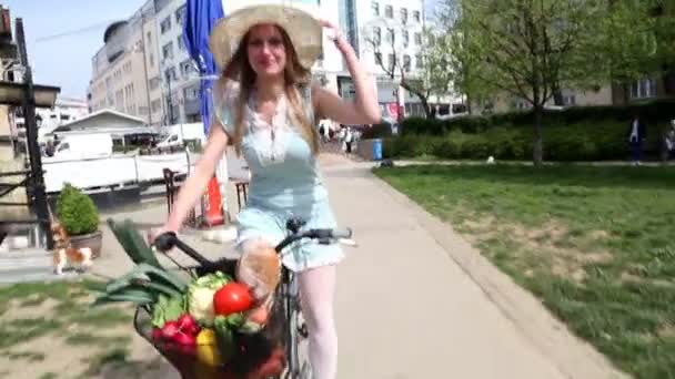Девушка ездит на велосипеде и держит шляпу — стоковое видео
