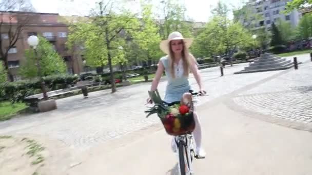 Flicka ridning cykel med korg full av grönsaker — Stockvideo