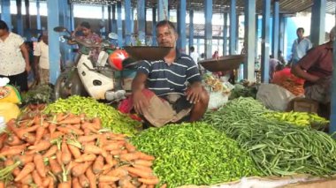 Sebze yığını üzerinde oturan adam