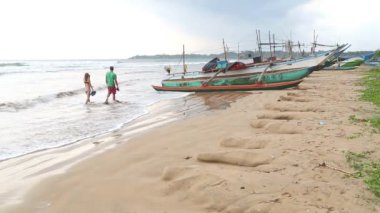 Geçen insanlar ile Weligama sahilde teknelerin görünümü