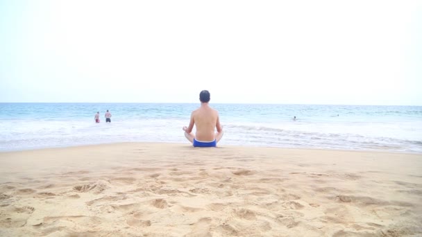 Człowiek jest medytując niedaleko Oceanu — Wideo stockowe