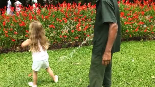 Chica lavando su juguete en el jardín — Vídeo de stock