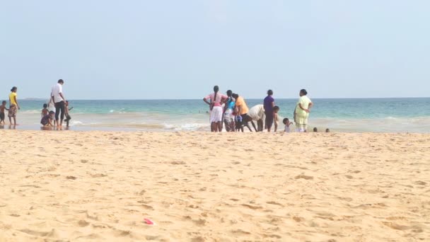 La gente del posto godersi la spiaggia e giocare nel surf . — Video Stock