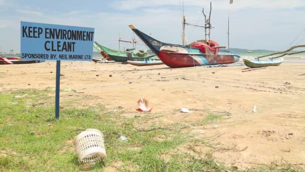 Vue des ordures laissées sur la plage avec des bateaux de pêche traditionnels en bois — Video