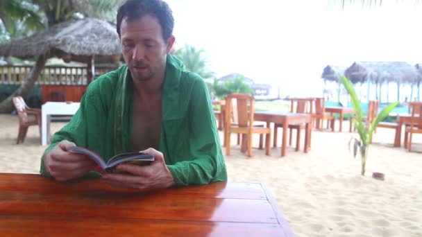 Man talking and reading a book in beach resort — Stock Video