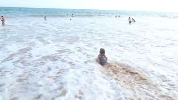 Petite fille jouant en vagues sur une plage — Video