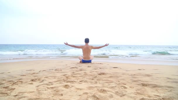 Mann meditiert in der Nähe des Ozeans — Stockvideo
