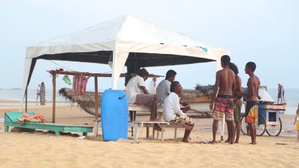 Local men standing and talking in front of surf stand. — Stock Video